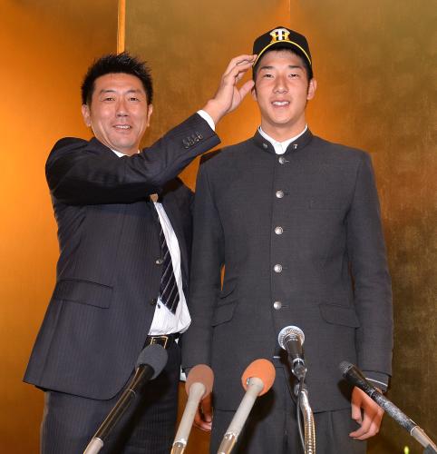 入団交渉を終え、田中スカウト（左）から帽子をかぶせられる横田慎太郎