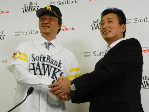入団会見した岡島（左）は小川編成育成部長とがっちり握手を交わす。