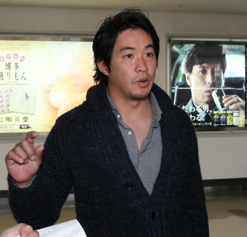 秋山監督を起用した広告の前で記者の質問に答える五十嵐