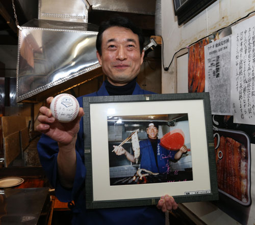 松井氏のうなぎ焼き体験の写真とサインボールを手に笑顔を見せる岩切さん