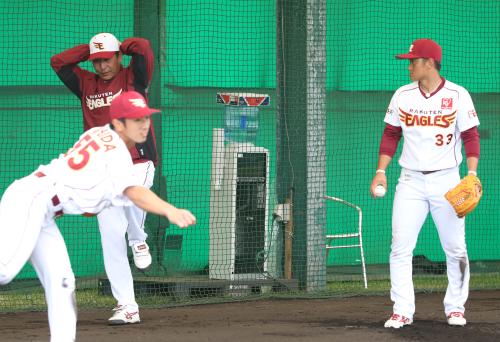ブルペンで佐藤投手総合コーチ（左）から投球指導を受ける銀次。手前は西田