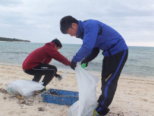 久米島の２軍宿舎近くのビーチでゴミを拾う楽天・美馬（右）
