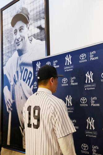 入団記者会見で、背番号「19」を披露する田中。左後方の写真は故ルー・ゲーリッグ内野手