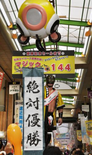 「日本一早いマジック点灯式」で「絶対優勝」と書かれた紙を持ちポーズをとる名誉応援団長の空牙さん