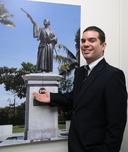 キューバ大使館のエントランスに飾ってある支倉常長の写真を紹介するダミアン・デルガド３等書記官
