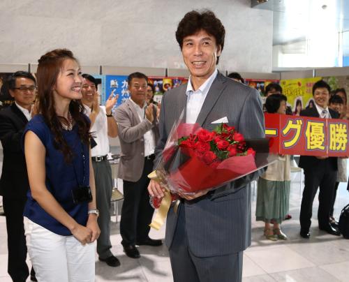 地元福岡・ＲＫＢ毎日放送の福田典子アナウンサー（左）から花束を受け取り笑顔の秋山監督