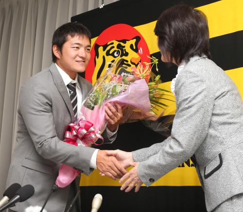 引退会見を終えた久保田（左）は女性球団職員から花束を受け取る