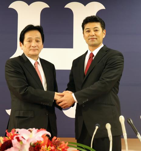 広島・緒方新監督は就任会見で鈴木球団本部長（左）と握手を交わす