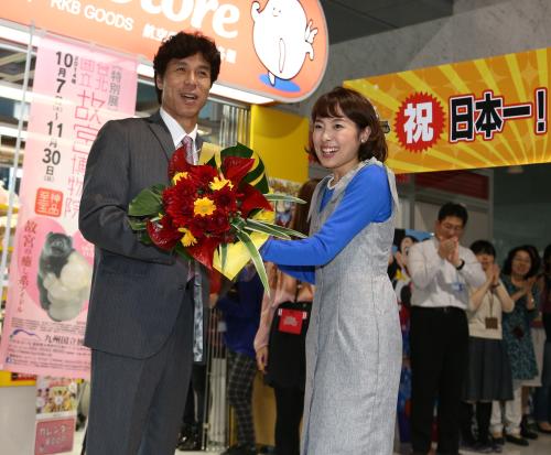 ＲＫＢ毎日放送「今日感テレビ」の武田アナ（右）から花束を受け取り笑顔の秋山前監督