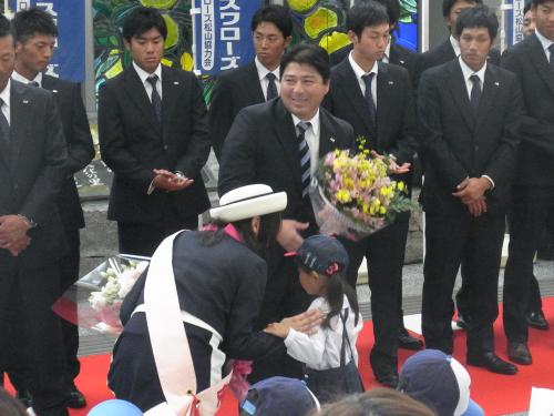 松山空港で行われた歓迎セレモニーで、幼稚園児から花束を受け取ったヤクルト・真中監督