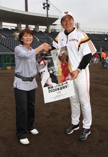 ９月３日、ソフトボール女子元日本代表監督の宇津木氏（左）の訪問を受けて、野球・ソフトボールの五輪復帰を目指すポスターの前で握手を交わす原監督