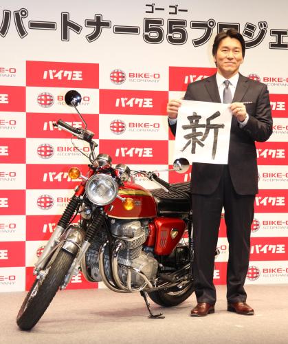 バイクの横で新年の抱負に「新」と書いた松井氏