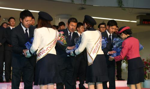 宮崎空港に到着し、日南サンシャインレディから花束を受け取る（左から）牧田、田辺監督、野上