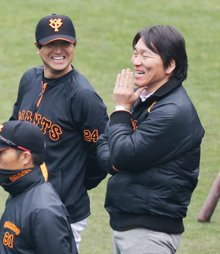 打撃ケージ裏で談笑する松井氏（右）と高橋由兼任コーチ