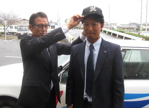 ロッテ６位指名の自動車運転指導員の梅田学園・信楽は山森スカウト（左）から帽子をかぶせてもらい「プロではスピードアップ、飛ばします」