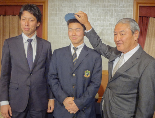 中田スカウト部長（右）から中日の帽子を被せられ、笑顔を見せる小笠原。左は佐藤スカウト