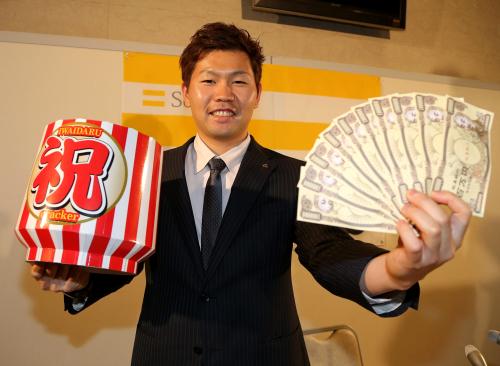 年俸１億円を突破し、祝い樽と現金のおもちゃを手に笑顔を見せる中村晃
