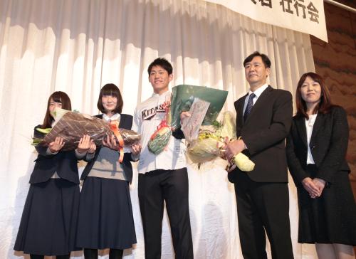 北須磨高校のユニホームを着てポーズを取る桜井俊貴（中央）と父・忠俊さん（右から２番目）、母・幸子さん（右端）と現マネジャー