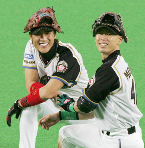 日本ハム時代、投手交代の際にグラブを頭に乗せ笑顔を見せる（左から）新庄と森本