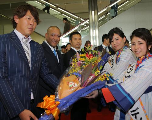 那覇空港で花束を贈られ、歓迎を受ける（左から）山口、ラミレス監督、池田球団社長