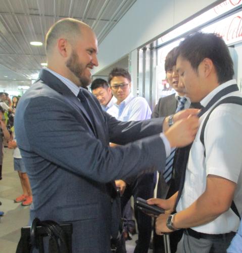 新千歳空港で青木広報のネクタイを締めてあげる日本ハム・レアード（左）