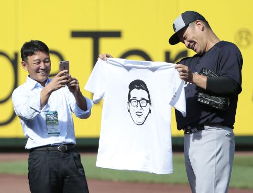 プロ野球楽天の立花球団社長（左）から贈られたＴシャツを広げ笑顔を見せるヤンキース・田中