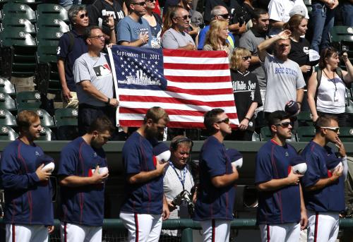 試合前の国歌斉唱でベンチ前に整列する選手と米国国旗を掲げるファン　（ＡＰ）