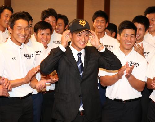 チームメイトに祝福されながら巨人の帽子をかぶる中京学院大・　吉川