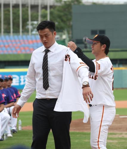 ＜巨人ＯＢ・台湾ＯＢ＞試合前のセレモニーで入団が決まった廖任磊（左）はひと足先に高橋監督からユニホームを着せてもらう