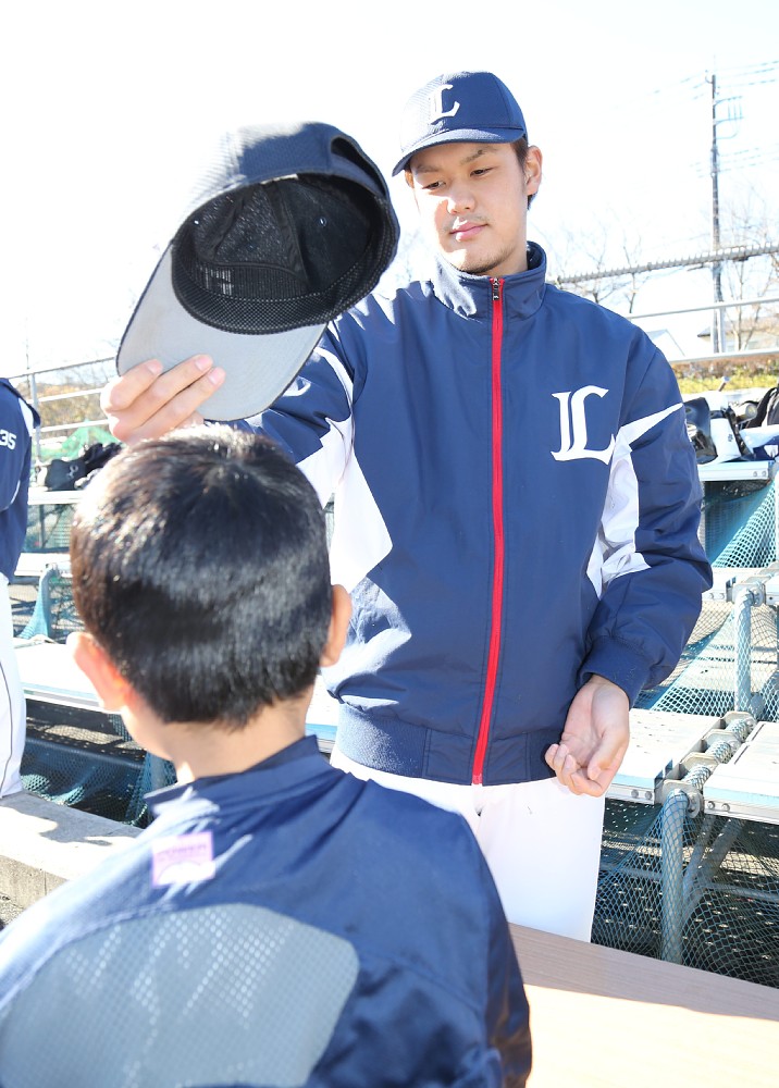 野球教室でじゃんけんで勝った子供に帽子をかぶらせてあげる高橋光成
