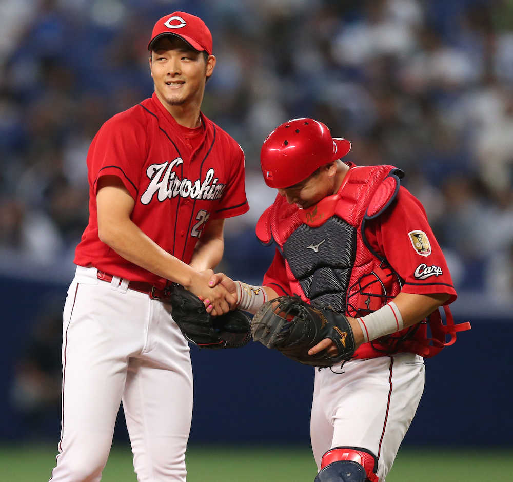 今季２度目の完封勝利を挙げ、会沢（右）と笑顔で握手をかわす薮田