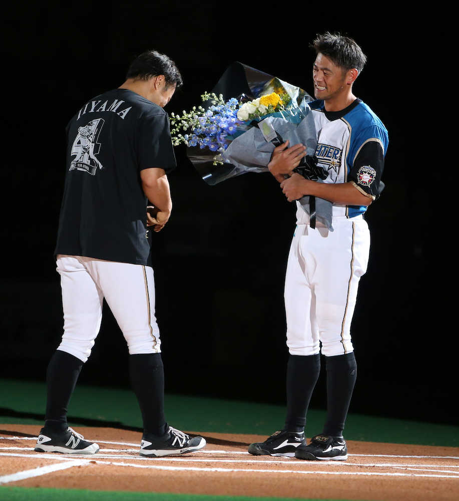 引退セレモニーで田中賢（左）から花束を渡され、涙ぐむ飯山
