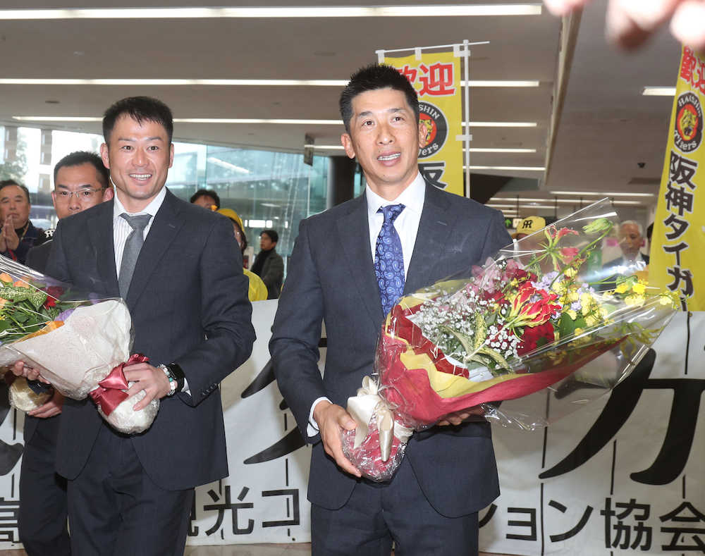 高知龍馬空港に到着し、花束を手に笑顔を見せる矢野２軍監督（右）と岡崎