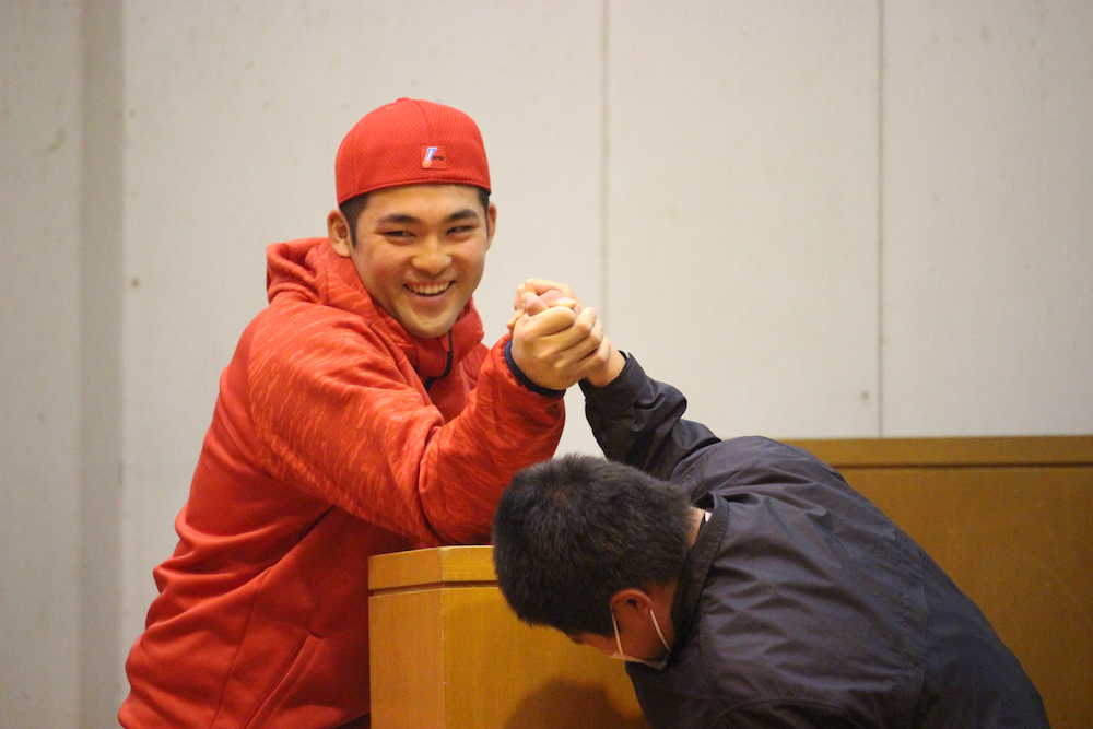 日南市立吾田東小学校の小学６年生と腕相撲対決を行い、余裕の表情で耐える永井（左）