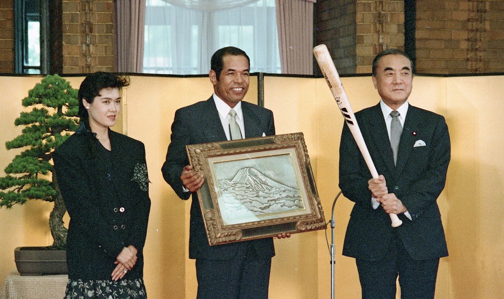 ＜国民栄誉賞表彰式＞富士山をかたどった調金のレリーフを手にニッコリの衣笠選手（中央）と正子夫人（左）。中曽根首相（当時）もプレゼントされたサイン入りバツトを持ちポーズ