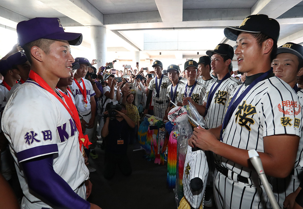 ７月２４日、決勝の試合後、千羽鶴を手に金足農・吉田（左）に激励のメッセージを送る明桜・山口