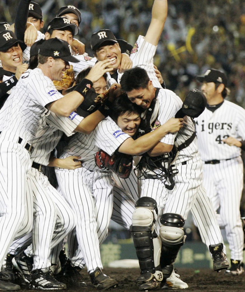 ２００５年９月２９日、胴上げ投手となった久保田（中央）と抱き合い喜びを爆発させる矢野（右）らナイン