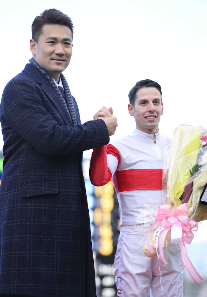 表彰式で握手を交わすＣ・デムーロ騎手と表彰式プレゼンターの田中（左）　　（撮影・田中　健作）