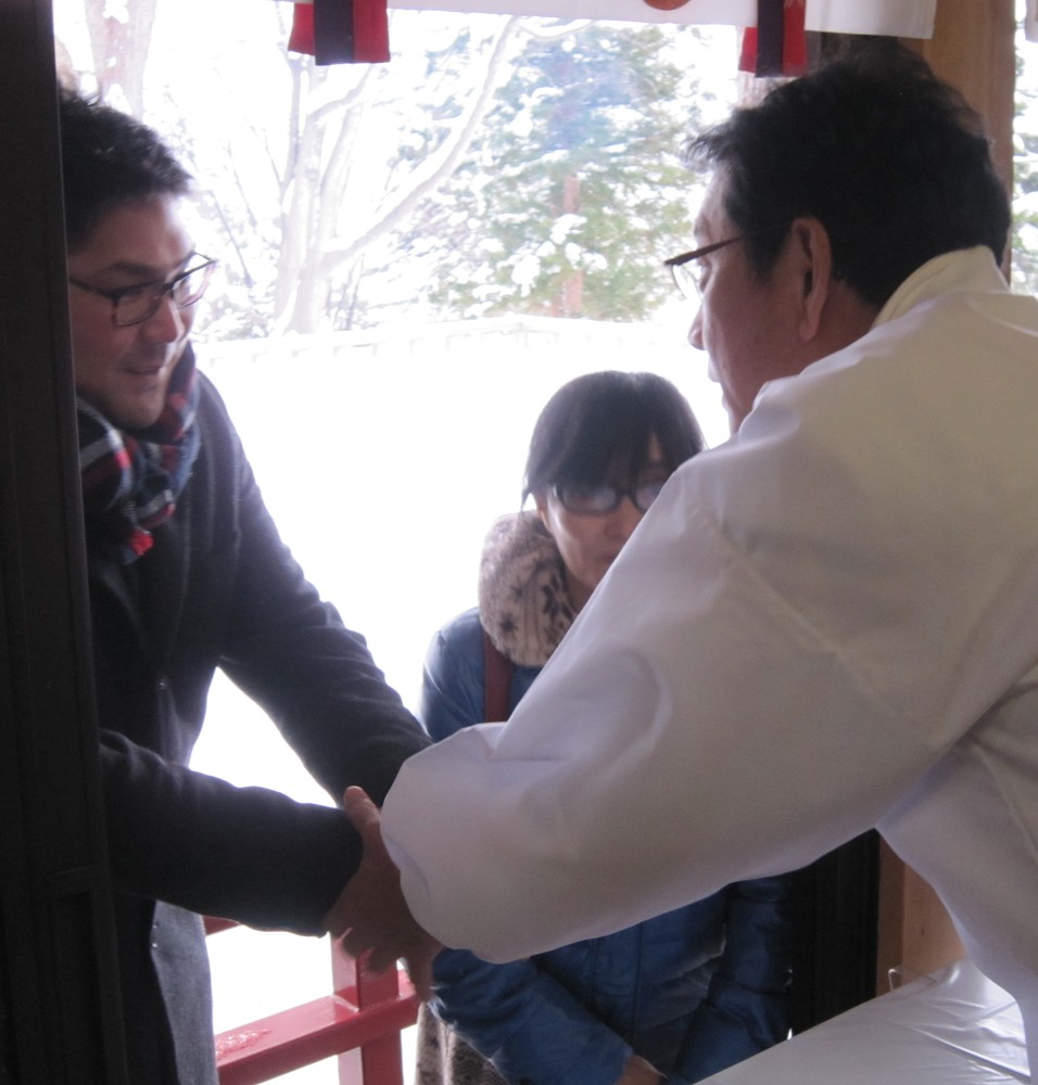 元日に仁木神社に初詣した本間氏（左）は参拝客を出迎える栗山監督と握手