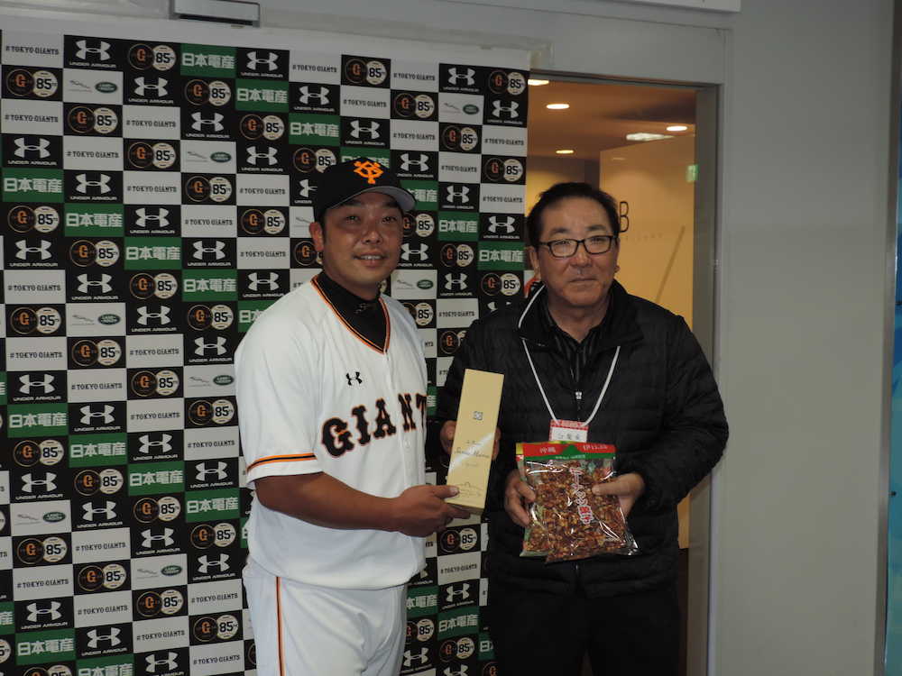 沖縄県伊江島の島袋村長（右）から名産のラム酒とピーナッツ菓子を贈呈された巨人・阿部