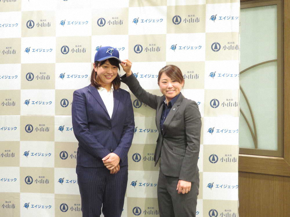 エイジェック女子野球部選手兼ヘッドコーチに就任した川端さん（左）は「ナックル姫」こと吉田監督から帽子をかぶせられる