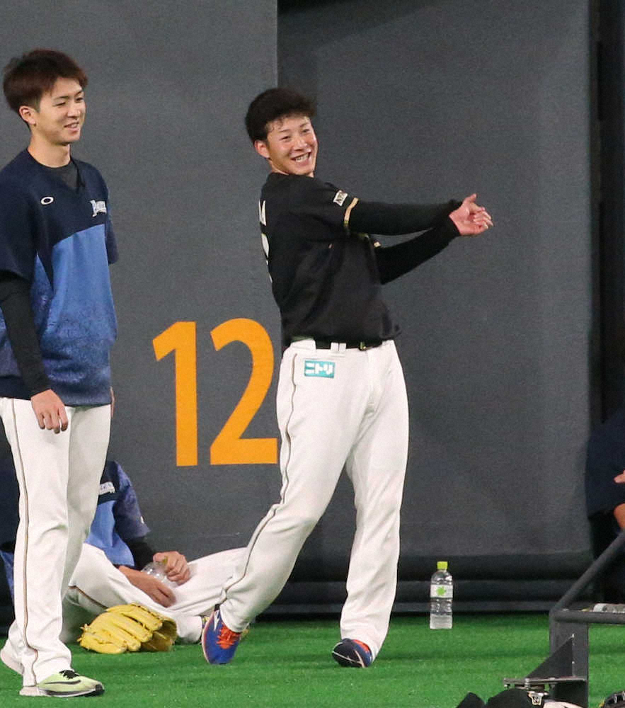 試合前練習で上沢（左）と談笑する吉田輝（撮影・高橋茂夫）