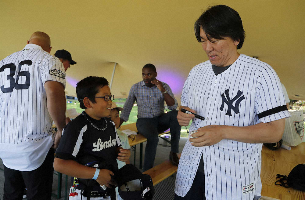 ロンドンで開催された野球教室に参加し、少年ファンのボールにサインするヤンキースOBでGM特別アドバイザーの松井秀喜氏（AP）