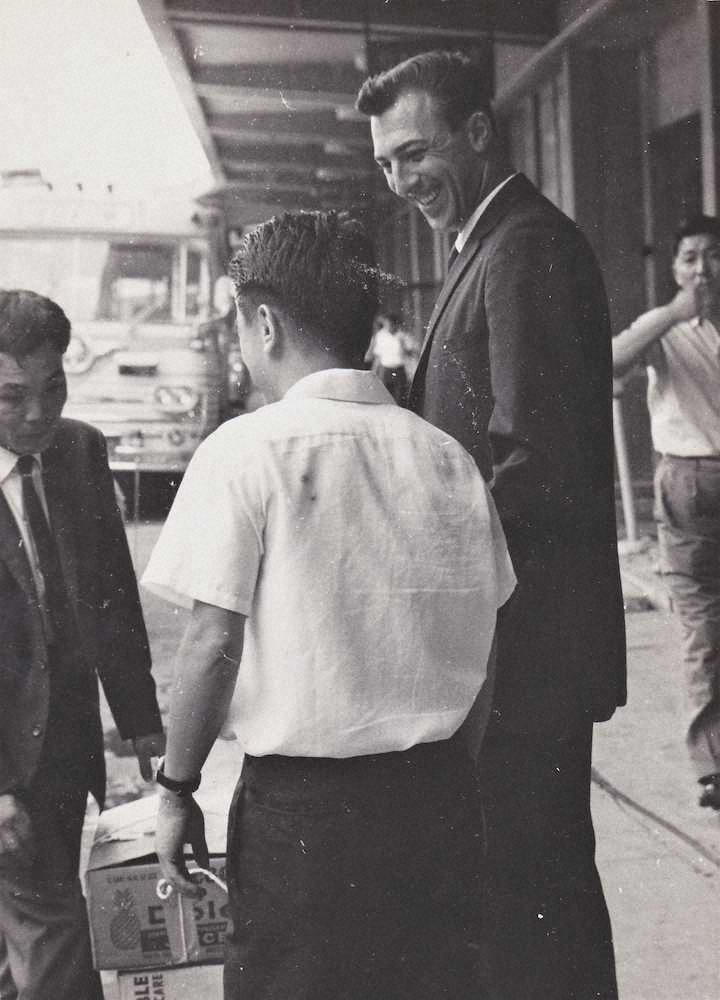 1962年7月18日、阪神入団テストを受けるためめ、羽田空港に降り立ったバッキー。有本義明さん（背中）の出迎えに笑顔を浮かべる＝有本さん提供＝