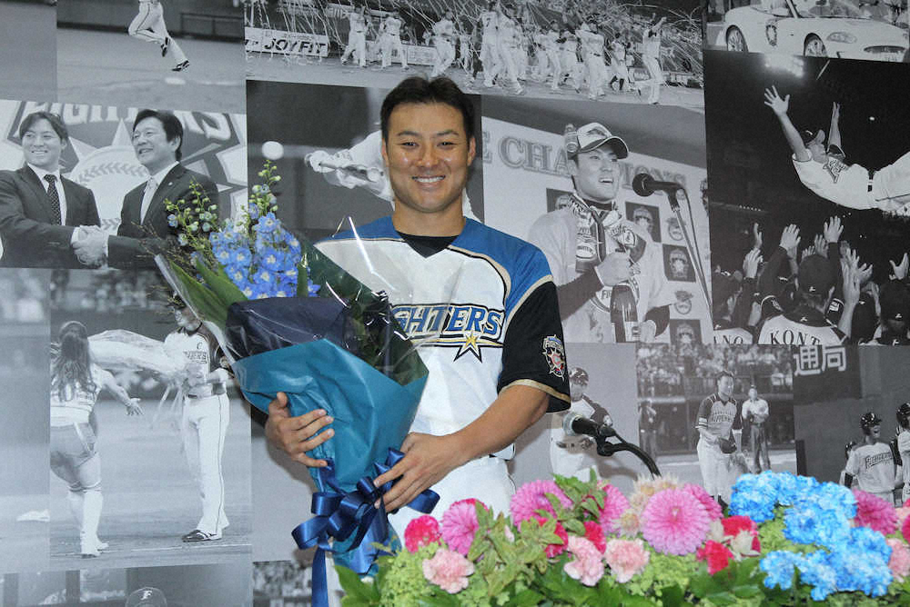引退会見後、日本ハム球団職員から花束を贈られ笑顔の田中賢（撮影・高橋茂夫）