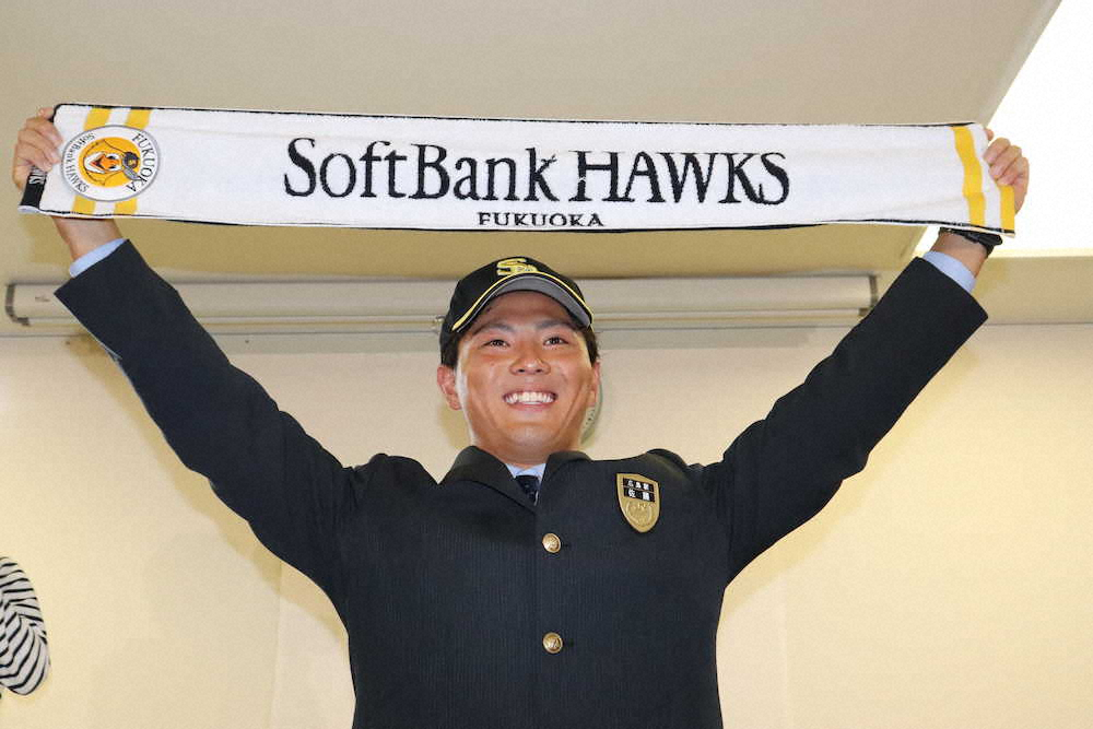 1位指名を受けたソフトバンクのタオルを掲げて笑顔をみせるJR西日本の佐藤
