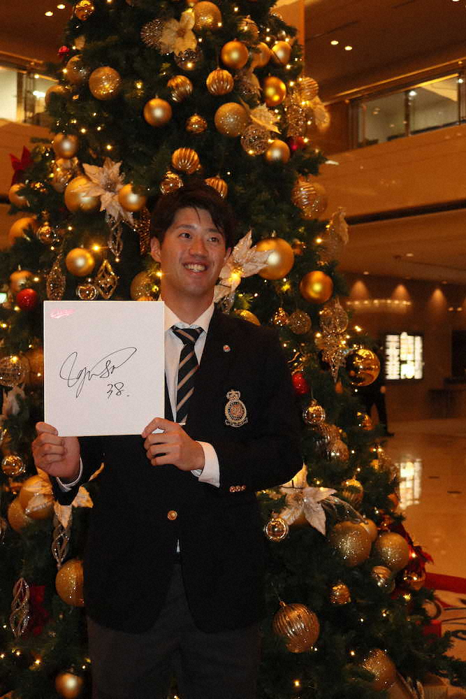 サイン色紙を手にクリスマスツリー前での記念撮影に応じる宇草