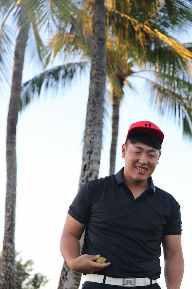 ハワイのヤシの木の下で実を手に持ち、笑顔を見せる巨人・岡本