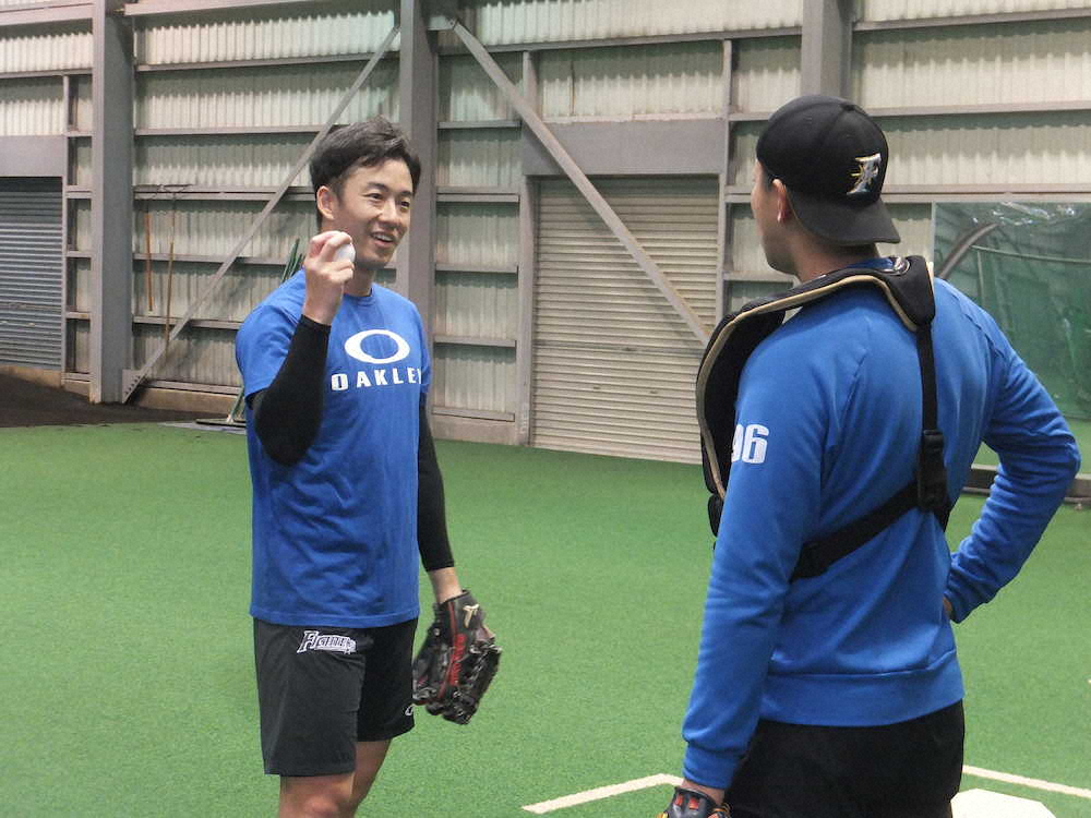 ブルペン捕手と新球のカーブについて談義する日本ハム・斎藤（左）