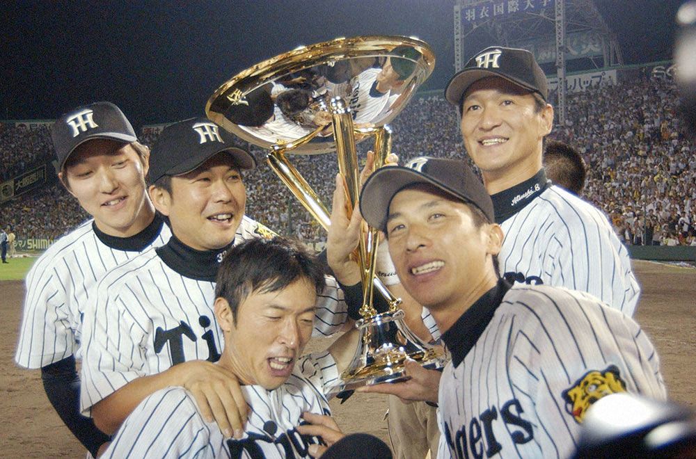 2003年9月15日の広島戦で18年ぶりのリーグ優勝を決め、優勝トロフィーを手に笑顔を見せる（右から）片岡篤史、矢野輝弘、桧山進次郎、久慈照嘉、吉野誠